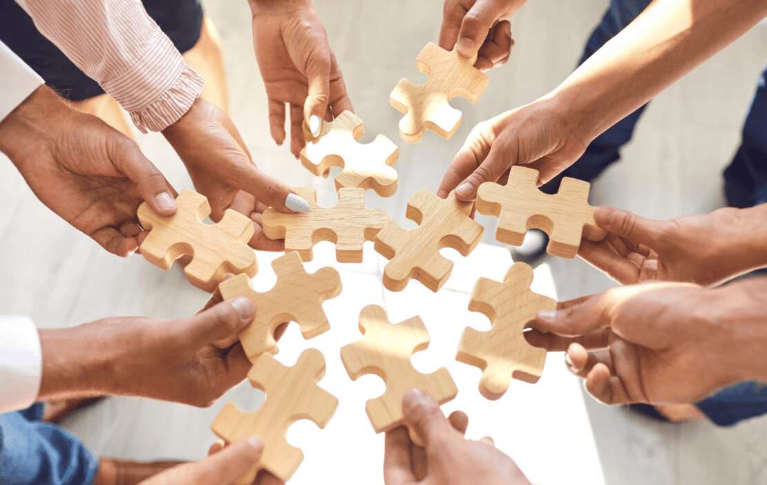ten people hold their hands in the air holding wooden puzzle pieces  